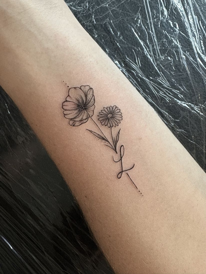 Zwei kleine Blumen mit Initiale am Unterarm