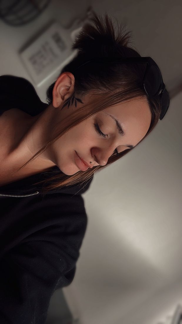 Jacky Janzen im Profil, mit einem kleinen Blätterzweig-Tattoo vor dem Ohr